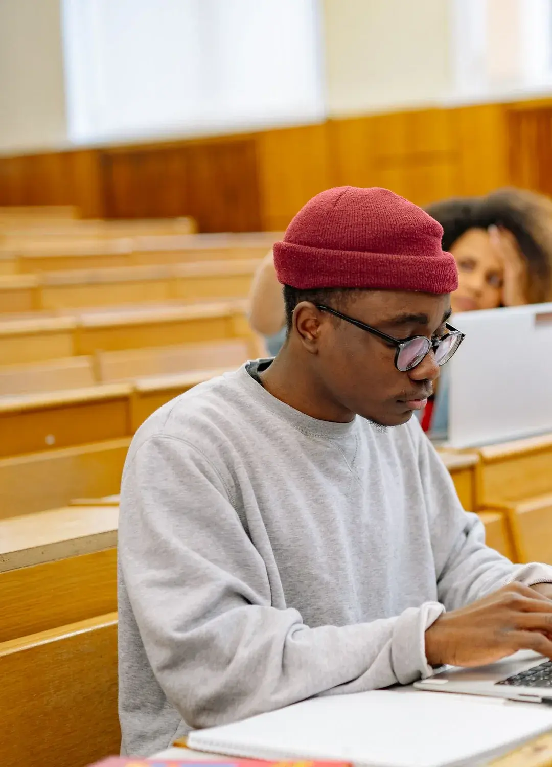 A learner working on a laptop in a lecture hall